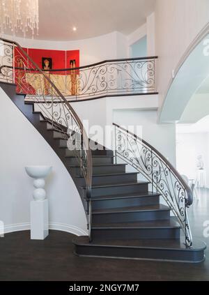 En regardant vers le haut escalier en colimaçon avec balusters en fer forgé sur le couloir à l'étage à l'intérieur d'une luxueuse maison. Banque D'Images