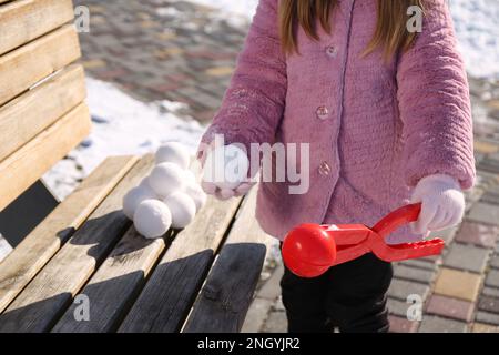 Petite fille jouant avec le fabricant de boules de neige à l'extérieur, gros plan Banque D'Images