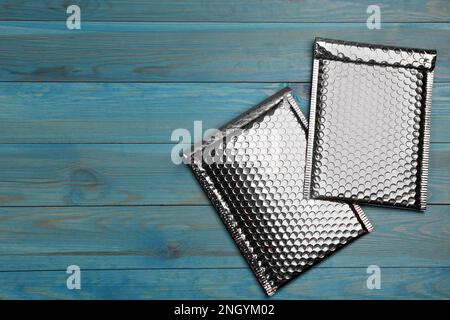 Deux enveloppes matelassées avec film à bulles sur fond en bois bleu clair, pose à plat. Espace pour le texte Banque D'Images