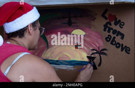 Un volontaire décore une boîte de lot lors de l'opération Christmas Drop 2022 Bundle Build à la base aérienne d'Andersen, Guam, le 3 décembre 2022. La mission d’OCD est de fournir de l’aide, des cadeaux et des marchandises à plus de 50 îles de l’océan Pacifique. Cette tradition de don se poursuit depuis 1952 et comprend plus de cinq pays partenaires qui travaillent ensemble à l'exécution de cette mission humanitaire. Banque D'Images