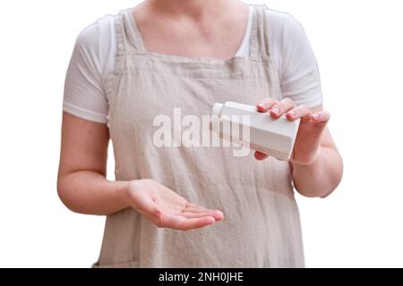 Un saupoudreuse de sel blanc dans les mains d'une femme dans la cuisine, isolée sur un fond blanc. Les mains des femmes tiennent un poivrier en céramique Banque D'Images