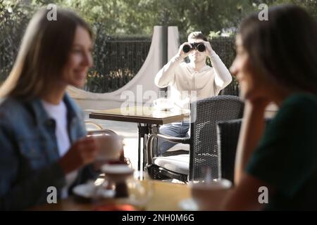 Un homme qui espionne sa petite amie dans un café en plein air. Tricherie Banque D'Images