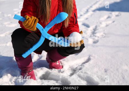 Petite fille jouant avec le fabricant de boules de neige à l'extérieur, gros plan Banque D'Images