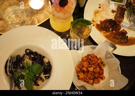 Pâtes à l'encre noire servies avec une peau de poulet croustillante et un steak de bœuf Banque D'Images