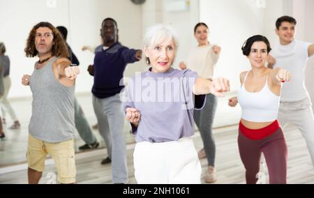 Femme âgée pratiquant des coups de poing pendant un cours d'auto-défense de groupe Banque D'Images