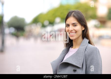 Une femme heureuse regarde un appareil photo dans la rue en hiver Banque D'Images