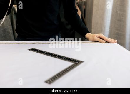 Sur mesure au travail. Couturière pour la confection de vêtements dans un studio moderne. Tissu de marquage sur mesure Banque D'Images