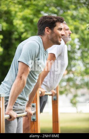 des hommes en salle de gym font des exercices sur la barre horizontale Banque D'Images
