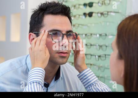 homme essayant de porter des lunettes dans un magasin optique Banque D'Images