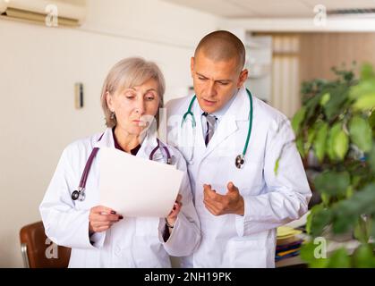 Deux médecins professionnels discutant de la carte médicale du patient Banque D'Images