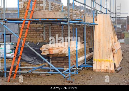 Poutres de toit en bois préfabriquées et traitées chimiquement hors site livrées avec des poutrelles de plancher en bois stockées prêtes pour la construction dans une nouvelle maison britannique Banque D'Images