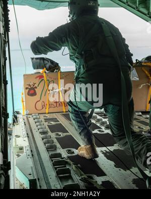 ÉTATS-UNIS Le sergent d'état-major de la Force aérienne Trevor Humes, maître de charge de l'escadron de transport aérien 36th, pousse un colis d'un Super Hercules C130J au-dessus de Falalop pendant l'opération Christmas Drop, le 6 décembre 2022. La livraison aérienne permet aux équipages de développer et de maintenir la préparation au combat par la production et la récupération d'aéronefs dans une région éloignée de l'océan Pacifique où les îles sont réparties dans une zone presque de la taille du continent des États-Unis. Banque D'Images