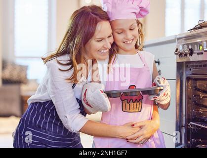 Je suis si fier de vous, miel. une jeune mère attrayante liant avec sa fille dans la cuisine à la maison pendant la cuisson. Banque D'Images