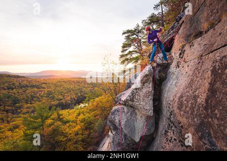 Homme se prépare à faire du rappel avec les montagnes et le feuillage en arrière-plan Banque D'Images