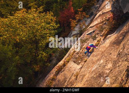 Homme escalade dans des couleurs vives pendant l'heure d'or de l'automne Banque D'Images