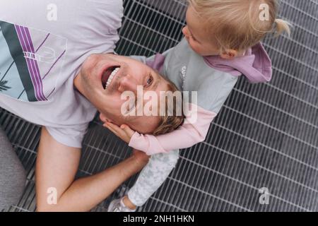 Un homme avec une petite fille qui se berce près du terrain de football Banque D'Images