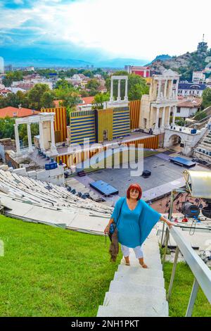 Femme âgée bénéficiant de la vue sur la ville de Plovdiv depuis l'ancien amphithéâtre de style romain restauré et accueillant aujourd'hui divers événements d'arts de la scène. Banque D'Images