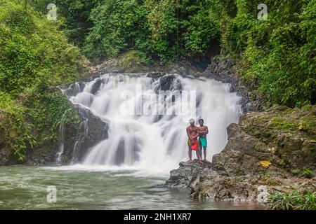 Deux jeunes hommes indigènes Embera en robe traditionnelle se tiennent près d'une cascade sur la rivière Chagres au Panama. Banque D'Images
