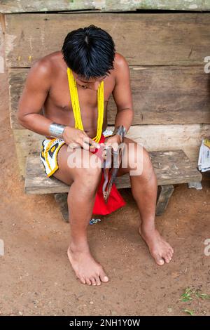 Un Embera indigène en robe traditionnelle porte une statue de grenouille en bois au Panama. Banque D'Images