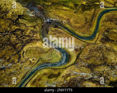 Vue aérienne d'un paysage rural, avec une longue route sinueuse flanquée d'une végétation luxuriante et d'une rivière de chaque côté Banque D'Images