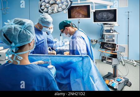 Chirurgiens travaillant sur le patient dans la salle d'opération moderne de l'hôpital. Travail d'équipe en service chirurgical Banque D'Images