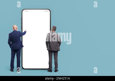 Les professionnels qui se trouvent devant un grand smartphone avec un écran vierge utilisent des applications mobiles Banque D'Images