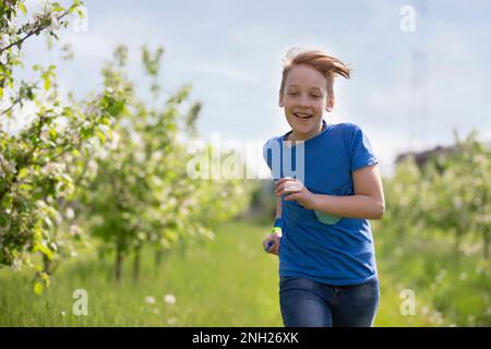 27 mai 2021. Biélorussie, Gomel, événement public. Un garçon heureux traverse le jardin de printemps. Banque D'Images