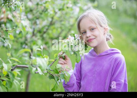 27 mai 2021. Biélorussie, Gomel, événement public.Une belle petite femme blonde pose dans un jardin de printemps sur le fond d'un pommier en fleur. A c Banque D'Images