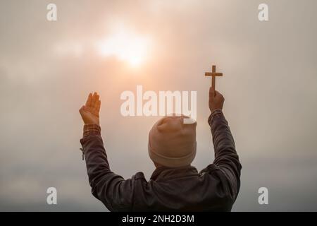 La main humaine tient la croix et la paume ouverte de culte. Eucharistie la thérapie bénir Dieu aidant à se repentir Catholique Pâques Carême prier. Christian concept backgrou Banque D'Images