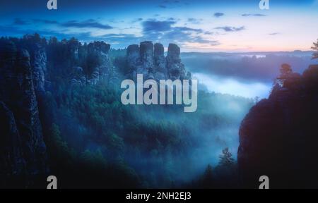 Vue du matin froide et brumeuse sur les sommets de Ganfelsen partie des montagnes de grès d'Elbe près du pont de Bastei (Basteibrucke) - Saxe, Allemagne Banque D'Images