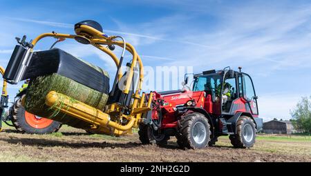 Enrubannage de grosses balles d'ensilage avec un équipement à l'avant d'un chargeur. Dumfries, Écosse, Royaume-Uni. Banque D'Images