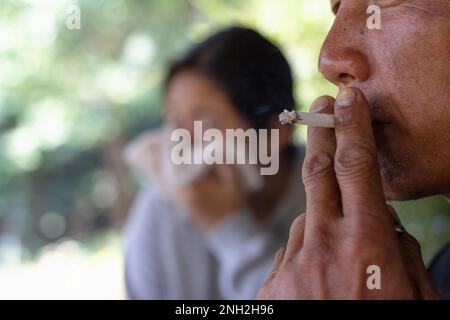 Concept de tabagisme passif. L'homme fume de la cigarette et la femme couvre son visage. Les concepts cessent de fumer dans les lieux publics. Banque D'Images