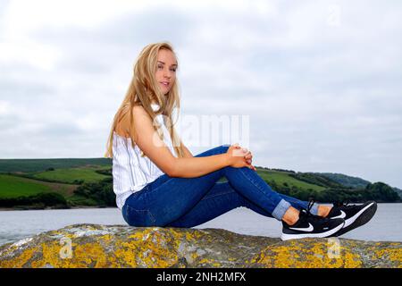 Lors d'une belle journée d'octobre à Wormit Beach, Fife, Rhianna Martin se trouve sur de grandes rochers au bord de la rivière Tay, en Écosse Banque D'Images