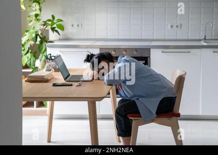 Une femme indépendante asiatique épuisée a surtravaillé fatiguée du travail ou de l'étude sur ordinateur portable s'est endormi sur la table. Banque D'Images