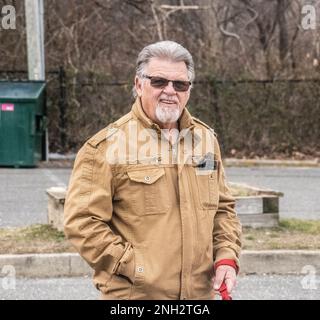 Homme portant des lunettes de soleil avec verres de transition, tenant sur la laisse de chien. Banque D'Images