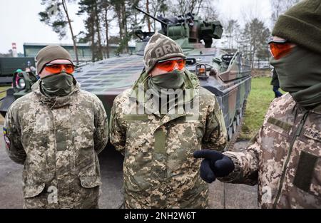 20 février 2023, Basse-Saxe, Munster : trois soldats ukrainiens se tiennent devant un véhicule de combat d'infanterie Marder lors d'une visite du ministre allemand de la Défense Pistorius à l'école de troupe de chars de Munster, Basse-Saxe. Au cours de sa visite à Munster, Pistorius apprend l'entraînement des soldats ukrainiens sur les principaux chars de combat allemands et les véhicules de combat d'infanterie et discute avec des soldats ukrainiens et des instructeurs allemands. Photo: Christian Charisius/dpa Banque D'Images