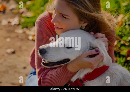 Belgrade, Serbie. 10 novembre 2022. Belle jeune femme embrassant son adorable retriever d'or, qui rassemble leurs visages, un jour ensoleillé. Banque D'Images