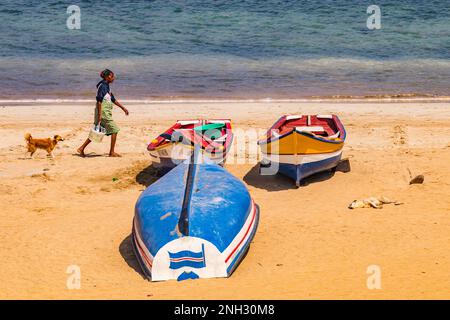 Une femme et deux chiens à côté de trois petits bateaux sur la plage de Tarrafal, île de Santiago, îles du Cap-Vert Banque D'Images