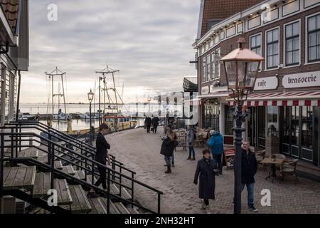 En hiver, les touristes se promènent à côté de cafés sur la promenade du front de mer, dans la ville de Volendam, aux pays-Bas. Banque D'Images