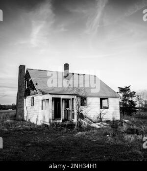 Maison abandonnée en chute, baignée de lumière du soleil le soir. Banque D'Images