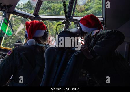 (De droite à gauche) le lieutenant-colonel Kira Coffey, commandant de l'escadron de transport aérien expéditionnaire 36th, et le major Chelsie Jones, pilote C-130J 36th de l'EAS, se sont emparées vers des membres de la communauté insulaire au-dessus de l'atoll Nomwin dans l'État de Chuuk, États fédérés de Micronésie, le 9 décembre 2022, pendant l'opération Christmas Drop 2022. L'avion, le callsign SANTA 67, a été le dernier vol de la mission OCD 2022. Banque D'Images