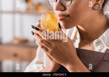 vue rognée de l'artisan afro-américain appréciant le parfum du savon fait main dans un atelier flou, image de stock Banque D'Images