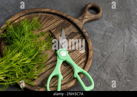 ciseaux de cuisine découpe de l'aneth dans la cuisine sur une planche à découper Banque D'Images