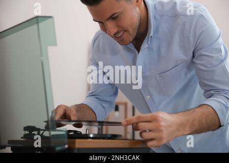 Joyeux homme à écouter de la musique avec la platine à la maison Banque D'Images