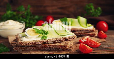 Pain de seigle frais avec œufs de caille, fromage à la crème et tranches de concombre sur une table en bois Banque D'Images