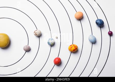 Composition de pose plate avec des pierres colorées sur fond blanc représentant le système solaire Banque D'Images