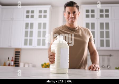 Homme avec une bouteille de lait de gallon à la table en marbre blanc dans la cuisine Banque D'Images