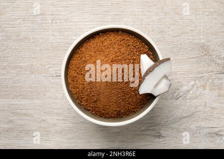 Sucre de noix de coco naturel dans un bol sur une table en bois blanc, vue du dessus Banque D'Images