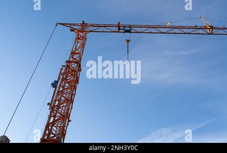 Grande grue de construction orange avec ciel bleu ensoleillé l'après-midi en arrière-plan Banque D'Images