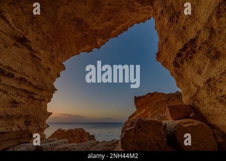 Grottes creusées dans le tuf jaune dans la falaise de Bue Marino aux premières lumières du matin, Favignana Banque D'Images